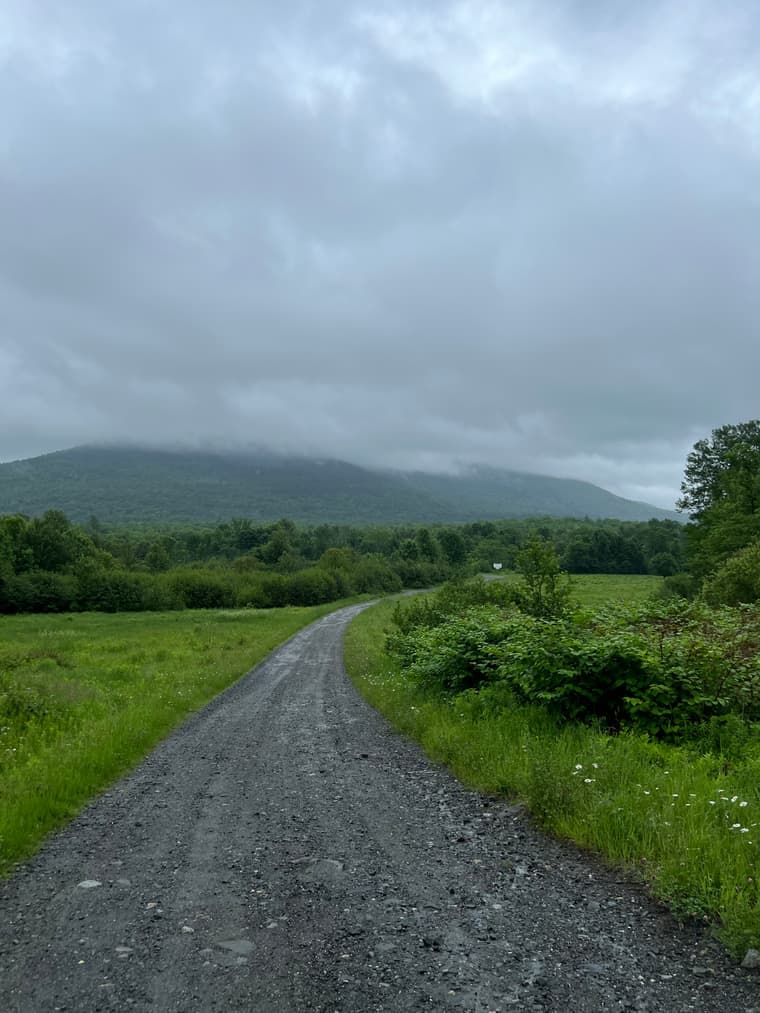 A gravel two-track winding toward a fog-draped ridge